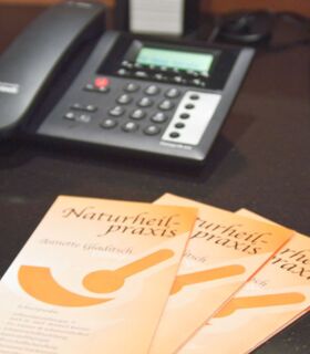 Telefon mit Flyer der Naturheilpraxis Gladitsch Telefon mit Flyer der Naturheilpraxis Gladitsch